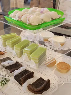 Display stand with mochi, green pandan layered slices, black sesame mochi cake and pineapple cakes