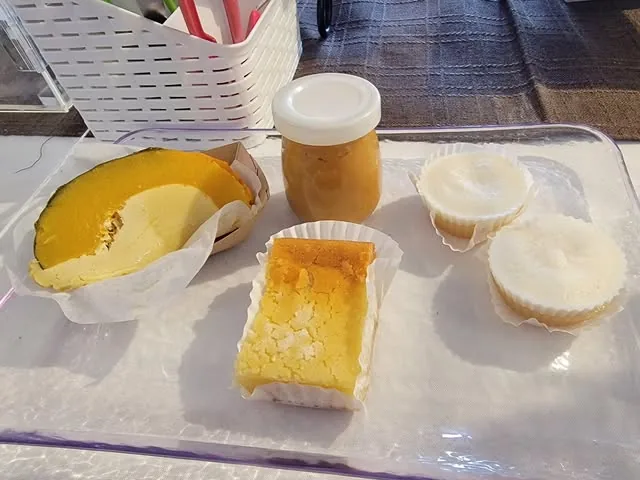Squares and cups of custard-style sweets on a clear tray at the market